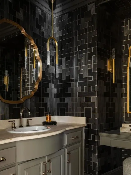 Another angle of the 'Fretwork' powder room, highlighting the interplay of the geometric wallpaper with the curved mirror and modern lighting. The design creates a sense of drama and luxury in a compact space.
