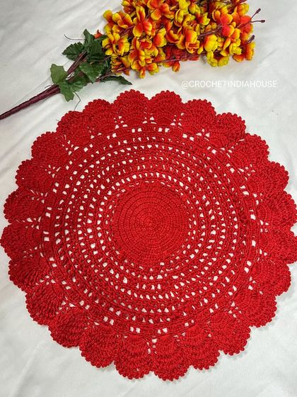 This large, solid red crochet doily with an intricate lace-like pattern and scalloped edge makes a beautiful statement piece as a tablemat or thali cover.
