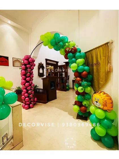 This jungle-themed balloon arch was a fun way to welcome guests to a 'Wild One' first birthday party. The mix of green and red balloons, along with a friendly lion foil balloon, sets a playful tone right from the entrance.