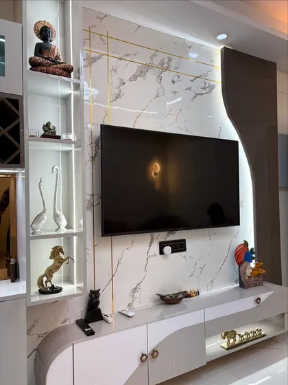 A detailed shot of the TV unit, showcasing the marble-finish panel with gold inlay, curved console, and backlit display shelves.
