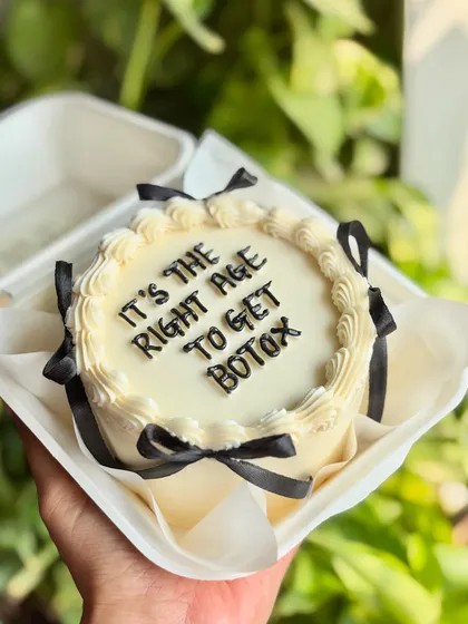 "It's the right age to get Botox." A witty and chic bento cake with black ribbons, perfect for a birthday celebration with a good sense of humor.