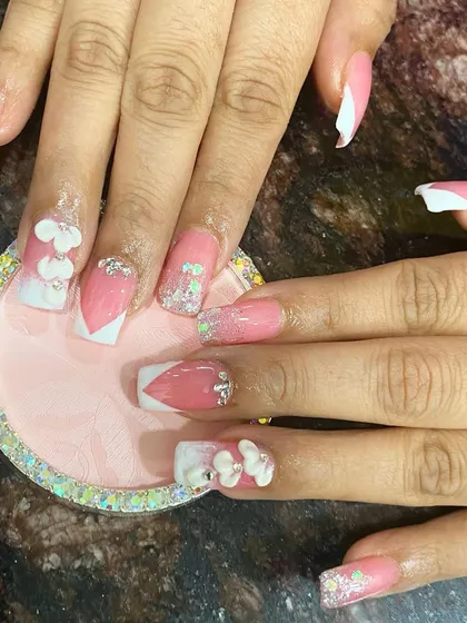 A fun and feminine pink and white set with 3D flowers, glitter, and heart-shaped tips.