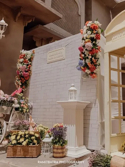 A beautiful decor setup with a European theme, featuring a white bicycle, abundant flowers, and a classic telephone booth.
