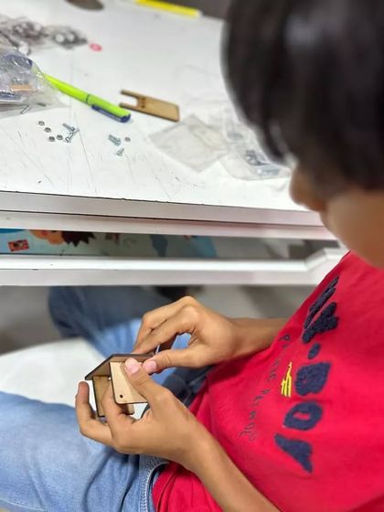 The concentration on this student's face says it all. He is carefully assembling a wooden project, learning the importance of precision, patience, and following instructions to build a functional electronic kit.