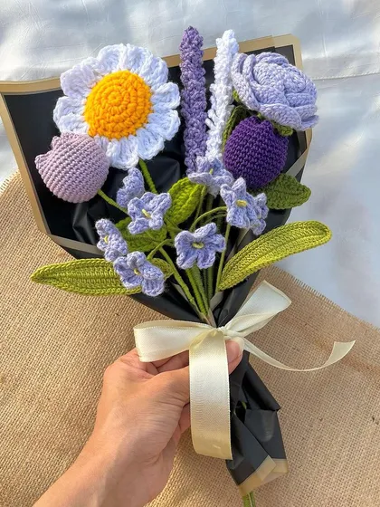 A hand holding our 'Lavender Love' bouquet, showing its size and intricate detail. It's a perfect handful of everlasting beauty.