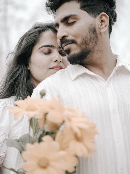 An artistic and romantic close-up of a couple, with a bouquet of yellow flowers in the foreground, creating a soft, dreamy effect.