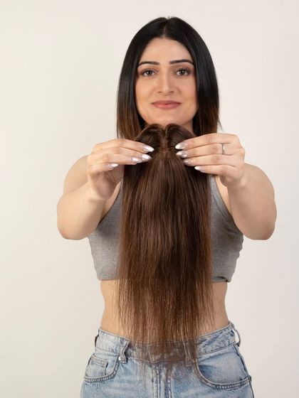 A model holding a hair topper, demonstrating the product's size and shape before application.