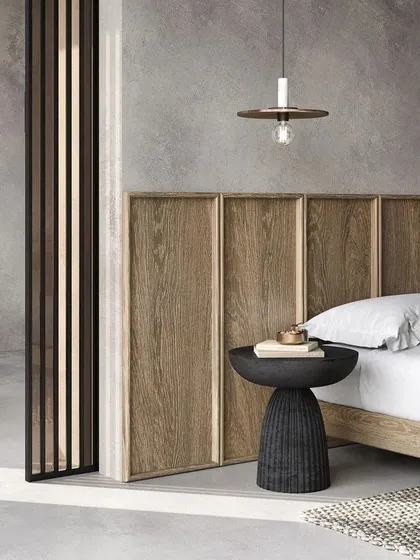 This image exemplifies serene, minimalist design. The clean lines of the wooden headboard, the simple pendant light, and the textured side table create a calming and uncluttered bedroom aesthetic that we often incorporate into our projects.