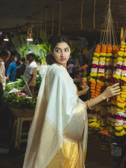 The colors and textures of a flower garland stall create a stunning backdrop for this portrait, capturing the essence of a traditional Indian market.