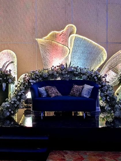A contemporary Sangeet stage with a deep blue velvet couch and a stunning backdrop of abstract, illuminated sculptures. The design is artistic and modern, creating a unique and memorable focal point.