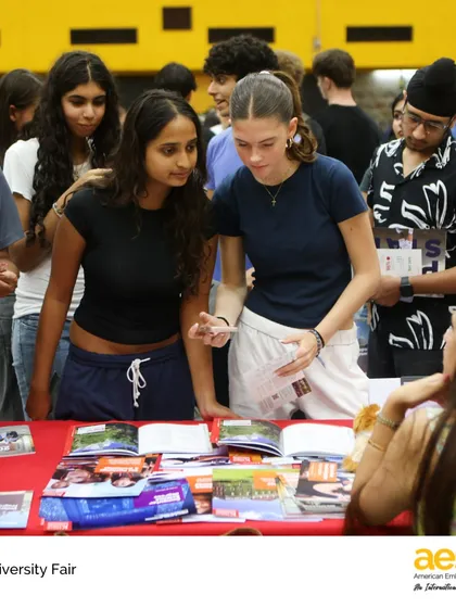 Two students collaborate as they review materials from a university booth. The fair is a chance for peer-to-peer discussion, helping students discover new possibilities and share insights about their college search.