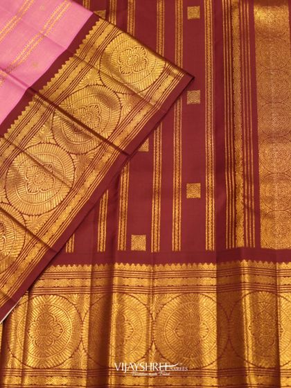A beautiful pink Kanjivaram with a contrasting maroon border and pallu, featuring large circular gold motifs that create a bold and traditional statement.