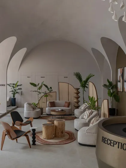 The reception area, where a curved desk and hanging pendant lights welcome visitors into the serene, vaulted space.