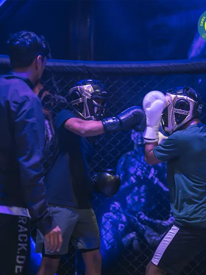 Two fighters sparring under the watchful eye of a coach. Training inside the cage prepares you for the intensity of real competition.
