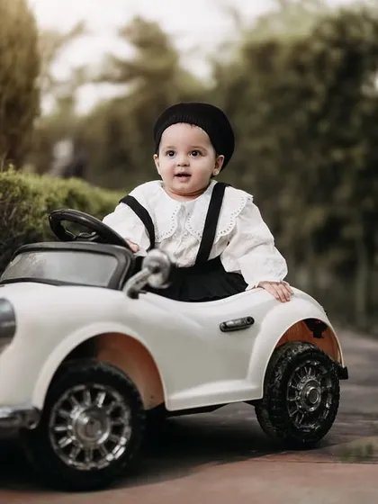 Looking cool and confident in her classic ride. This little girl is rocking a Parisian-chic look with her beret and suspenders, ready for a drive through the park.