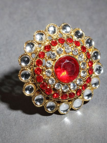 A vibrant adjustable ring with red and white stones in a circular pattern.