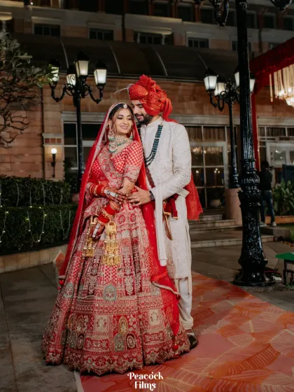 A classic portrait of the couple in their wedding attire, posing in the beautifully lit grounds of the venue at night.