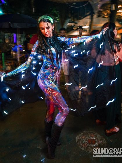 A performer wears a psychedelic bodysuit and a flowing cape embedded with lights. This act combines dance with light art for a mesmerizing, trance-like effect.