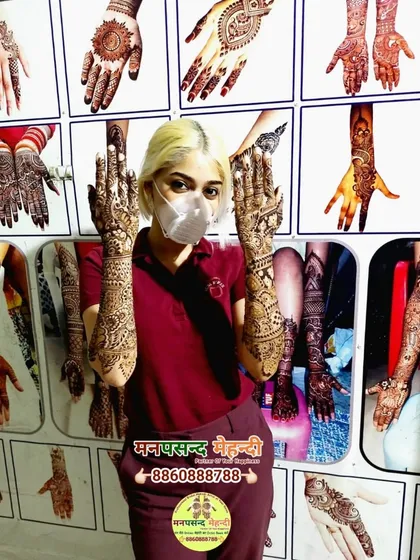 A client posing in front of our design wall, showcasing her full bridal mehndi. Our studio is a space for inspiration and beautiful transformations.