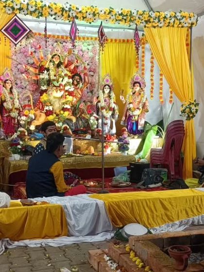 A traditional pandal decoration for a Durga Puja celebration, with yellow drapes and floral arrangements creating a festive and devotional atmosphere.
