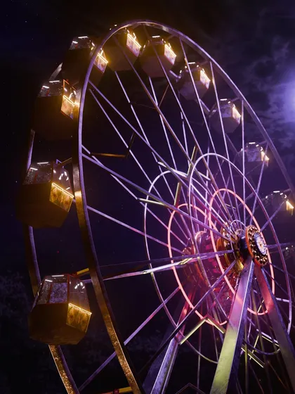 An exterior shot of the Ferris wheel at night. This view shows the full scale of the structure against a dark, cloudy sky, establishing it as a central, ominous landmark in the Karnival world.
