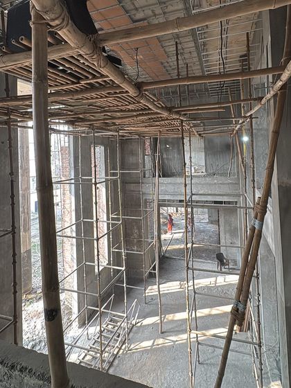 An overhead view of a large construction site, showing the concrete shell and scaffolding. This is the blank canvas from which a home with history, character, and warmth will emerge.