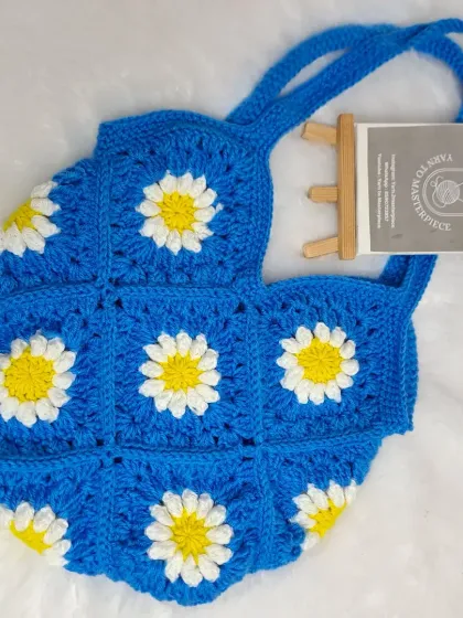 I love how the classic white and yellow daisies look against this vibrant blue. This granny square shoulder bag is perfect for casual outings and is handmade from soft but sturdy cotton yarn.