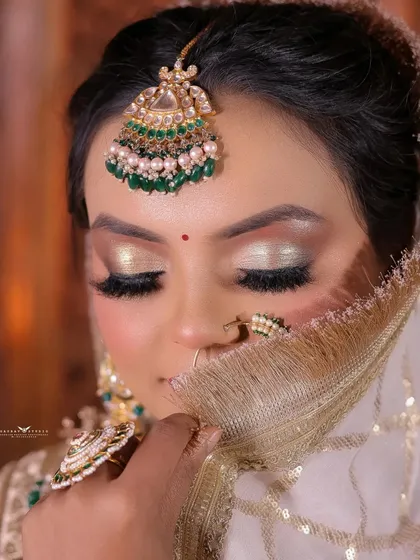 A close-up shot with the bride's face partially covered by her sheer dupatta, focusing on her striking eyes.