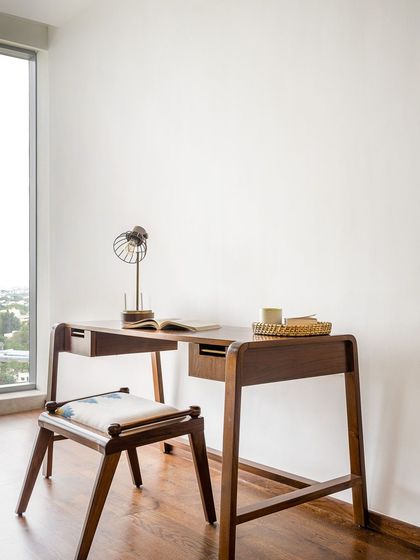 The Makam Study Table is a minimal and functional piece featuring brass rods as drawer handles. It provides a sleek and uncluttered workspace, perfect for a modern home office.