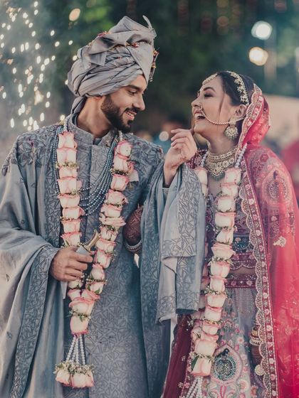A happy, candid moment between the couple after their varmala exchange, with beautiful rose garlands. Their smiles tell a story of love and friendship.