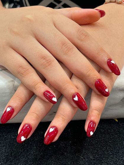 Spread a little love with our hand-painted heart nails. This classic red manicure gets a sweet update with tiny, perfect white hearts on each nail.