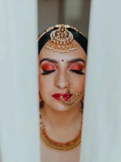 A close-up of the bride's makeup, with her eyes closed, framed by white curtains.