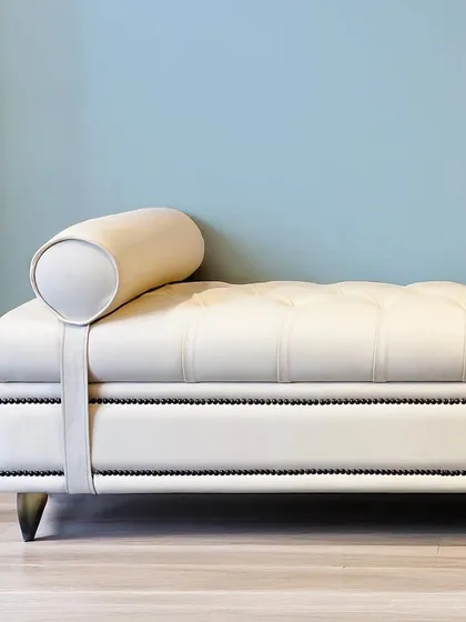 An elegant off-white upholstered bench designed for timeless sophistication. With its sleek silhouette, tufted seat, and classic bolster pillows, it’s a versatile piece that adds comfort and style to an entryway or bedroom.