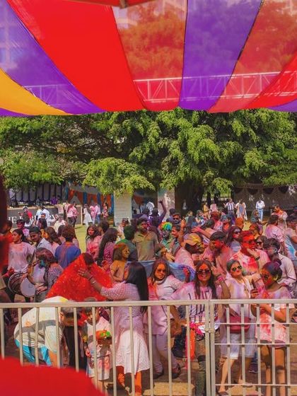 A view of the outdoor Holi party setup, with colorful banners and a large crowd. I manage all aspects of event decor and logistics for large-scale festivals.