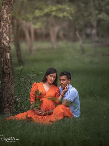 A couple sits together in the grass for a romantic outdoor maternity portrait. The way she touches his face creates a point of connection and intimacy in the frame.