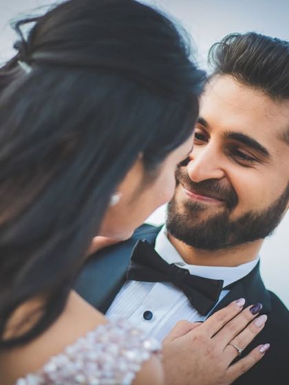 A close-up, happy portrait of a couple ready for their cocktail party. Their smiles show the excitement for the night ahead.