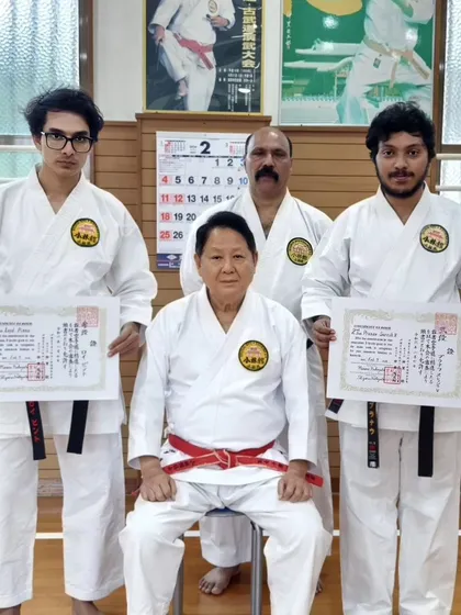 A formal photograph with my students and our grandmaster in Okinawa, proudly displaying their new Dan certificates.