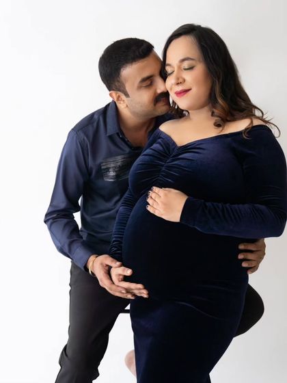 A tender moment with the partner embracing the mom-to-be from behind, both with joyful expressions.