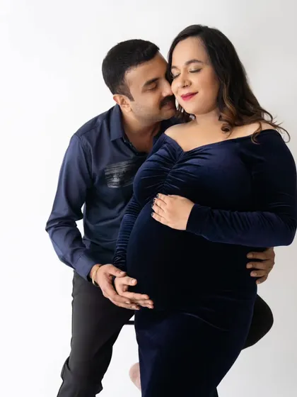 A tender moment with the partner embracing the mom-to-be from behind, both with joyful expressions.
