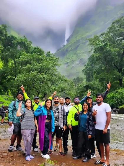 The group posing in front of the mighty Kalu waterfall, with the mist from the falls creating a dramatic backdrop.