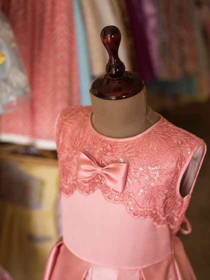A close-up shot of a pink satin and lace dress on a mannequin in my studio. This view highlights the delicate texture of the lace and the perfect placement of the bow.