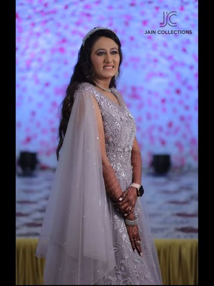 A client looking elegant in a grey gown with cape-like sleeves. The intricate beadwork and flowing silhouette make it a stunning choice for an evening event.