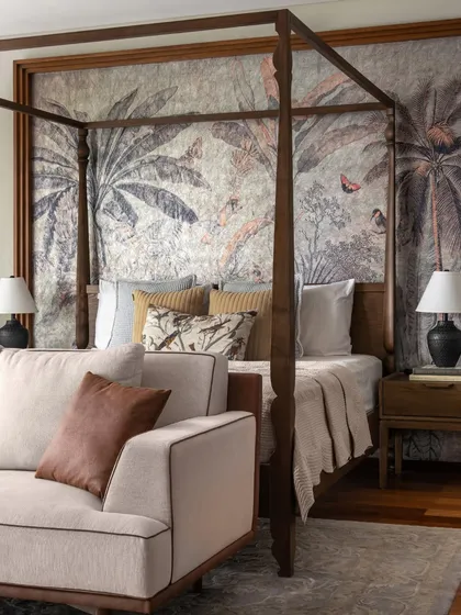 In this master suite, the four-poster bed creates an intimate sanctuary within a large, open room. I chose a botanical wallpaper to serve as a dramatic, artistic backdrop, adding depth and a connection to nature. It’s a perfect example of how we design multi-functional bedrooms that are not just for sleep, but for living and retreating.
