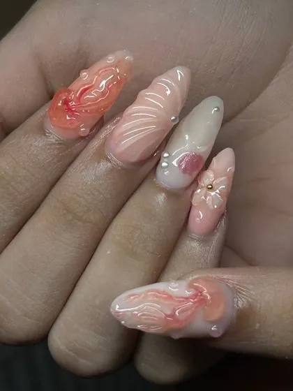 Another angle of the beach-inspired nail art, highlighting the different shapes and textures on each nail, from shells to flowers.