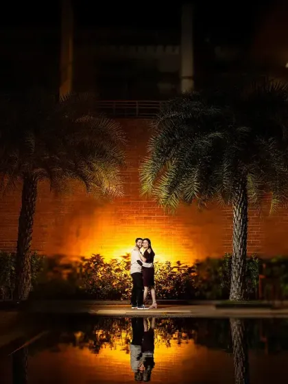 A beautiful night shot using the warm glow of a spotlight to create an intimate space for the couple. The reflection in the water below adds a lovely symmetry and doubles the romance.
