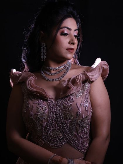 A moody, artistic shot of the model in the pink gown, showcasing the texture of the fabric and the sparkle of the jewellery under dramatic lighting.