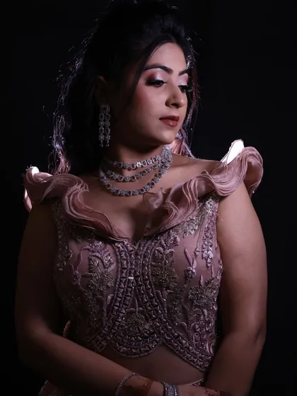 A close-up portrait of the model in the dusty pink engagement gown, showcasing the ruffled shoulders and detailed bodice against a black background.