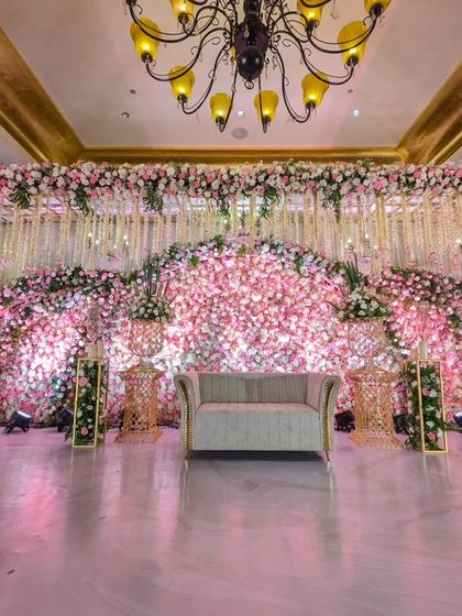 I designed this breathtaking reception stage with a massive, curved wall of pink and white flowers, creating an immersive and romantic backdrop for the couple.