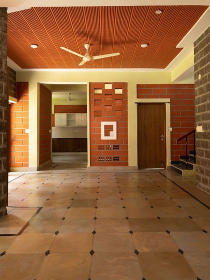 The interior living space features exposed stone and hollow clay block walls, with a patterned clay tile filler roof, showcasing a variety of sustainable materials.