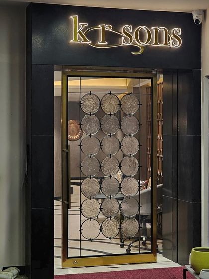 The entrance to KR Sons, a jewellery store in Ahmedabad, features a custom-designed door with textured glass discs set in a brass frame. This detail provides a hint of the opulence within while maintaining a sense of privacy and intrigue.